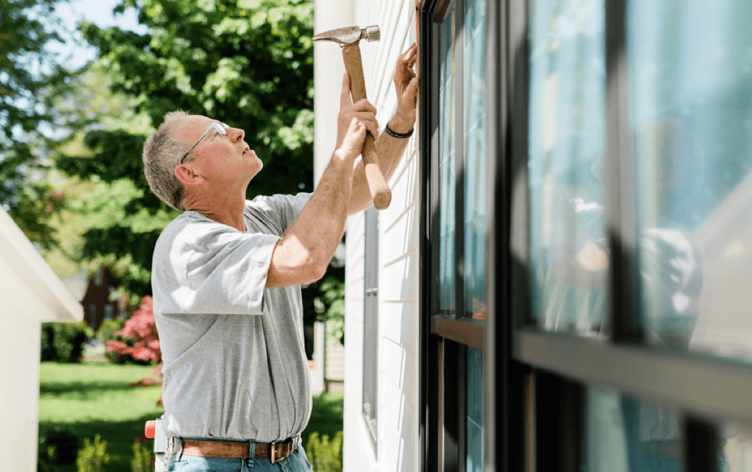 builder hammering in trim on a window